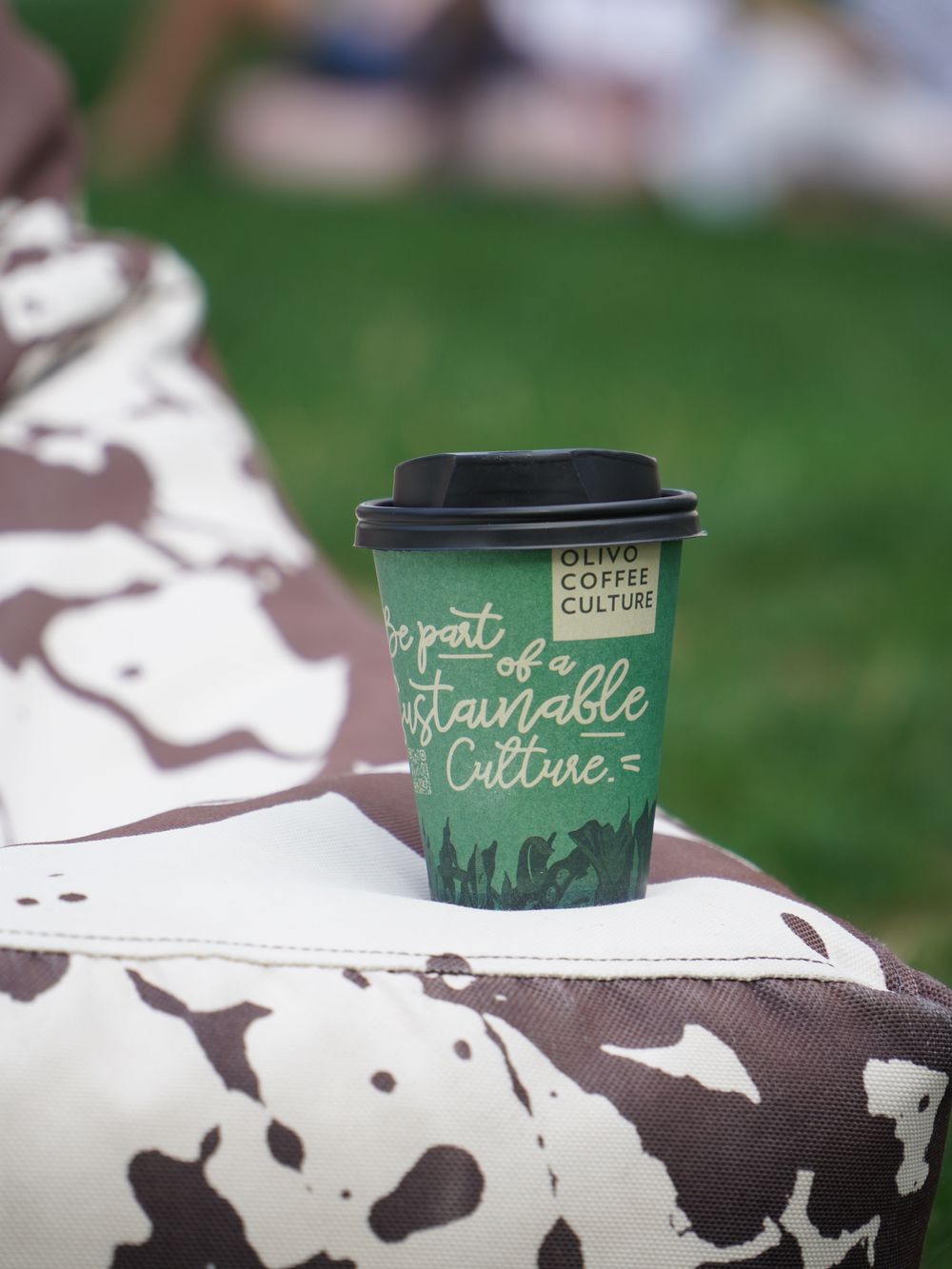 Pahar de cafea pe geantă, fundal verde
